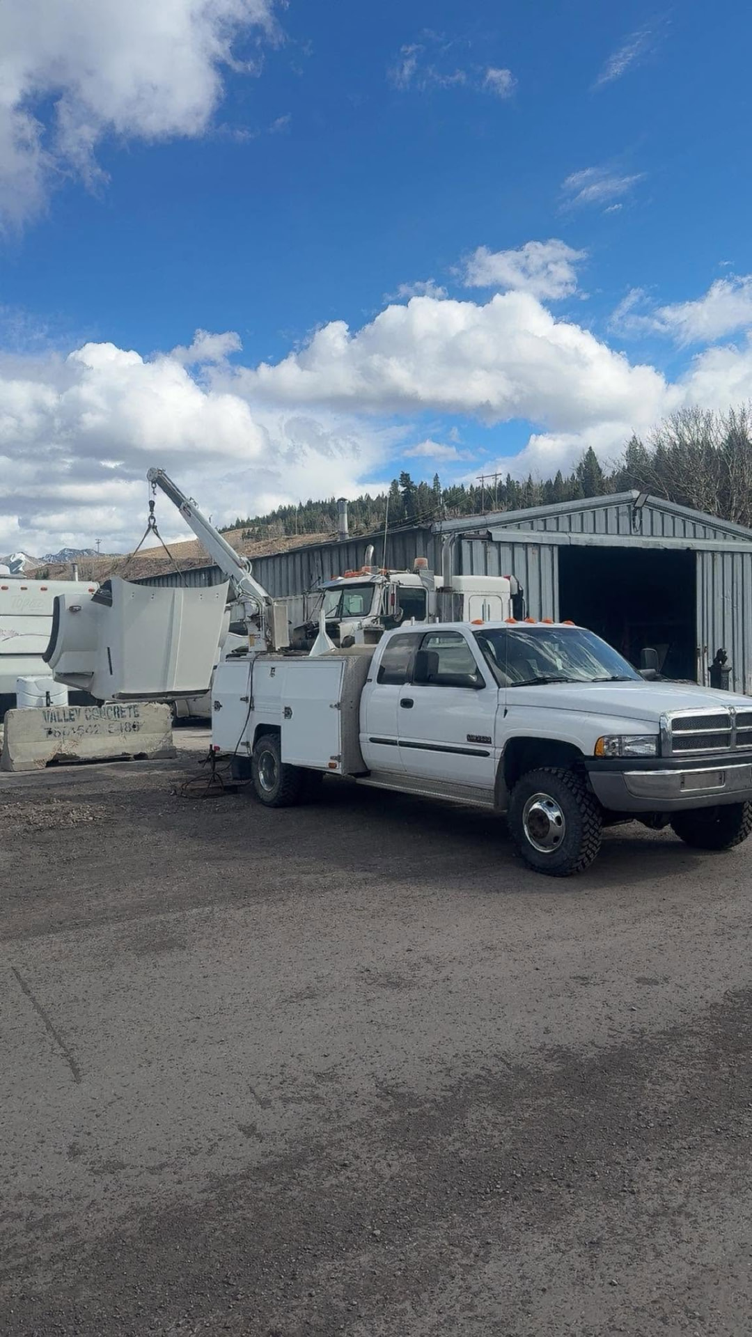 White Dodge Ram service truck with crane at a Crowsnest Pass work yard